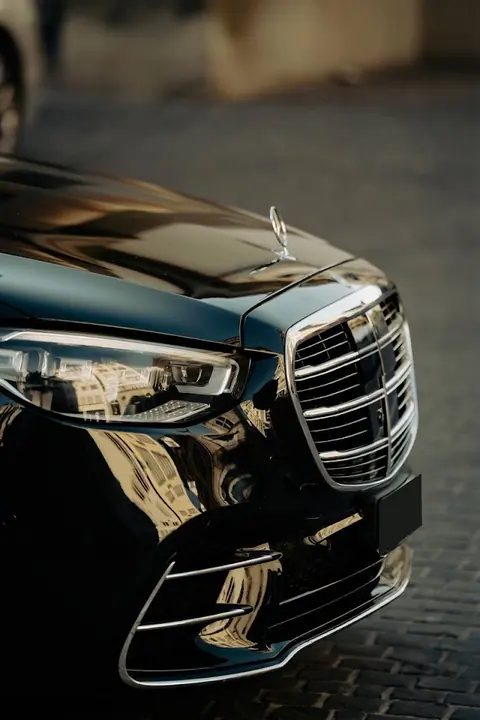 Schwarze Mercedes-Benz Limousine — Frontansicht mit Kühlergrill und Mercedes-Stern in goldenem Abendlicht