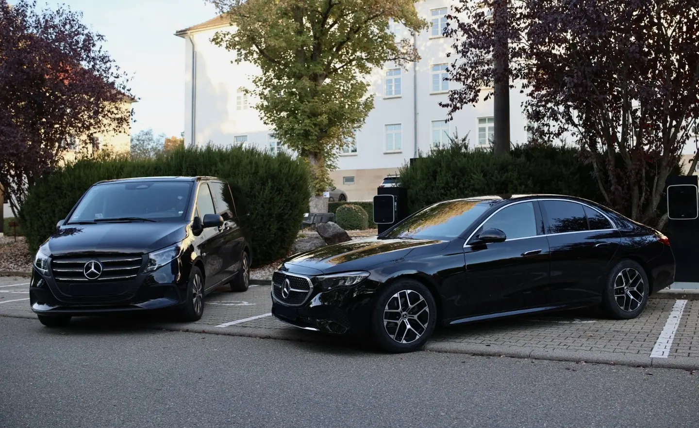 Schwarze Mercedes V-Klasse und E-Klasse an Ladesäulen vor einem Hotel — Chauffeurservice und Limousinenservice Stuttgart